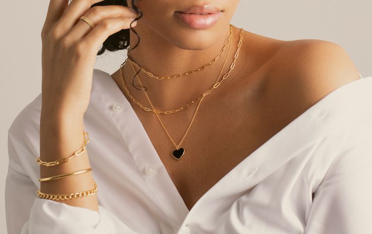 Woman in a white shirt wearing layered gold necklaces